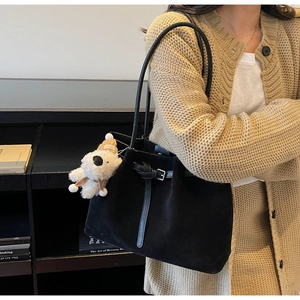 Dettaglio della borsa tote in pelle scamosciata nera con cinturino e ciondolo a orsetto