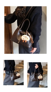 Detail view of dark brown leather Boston bag with plush sheep charm in lifestyle setting