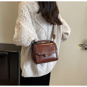 Detailed shot of brown vintage oil-wax leather bag with geometric woven shoulder strap