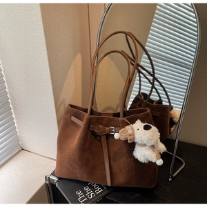 Dettaglio della borsa tote marrone opaca in pelle scamosciata con ciondolo a peluche
