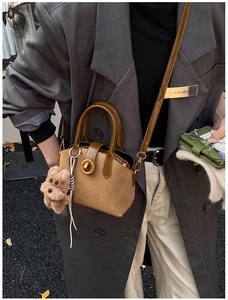 Detail of vintage brown suede shell bag with golden metal lock and plush bear charm