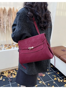 Detail of burgundy vintage briefcase bag with metal lock shown on autumn tweed coat