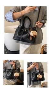 Detail of minimalist black tote bag with cute lamb charm and adjustable strap