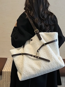 Elegante borsa tote in peluche bianco sporco con cinturini in pelle marrone indossata da modella
