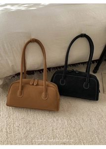 Détail de sacs portés épaule en daim vintage marron et noir sur un fond blanc épuré
