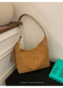 Close-up of camel suede tote bag texture with adjustable strap and metallic buckle