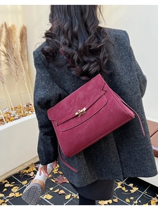 Close-up of a burgundy vintage briefcase with metallic twist lock and pebbled leather