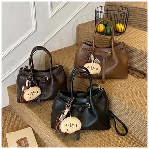 Chic trio of faux leather bucket bags in black, dark brown, and tan on tiered display