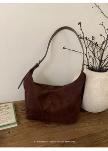 Detail of deep brown frosted leather hobo bag with smooth strap and silver metal buckle