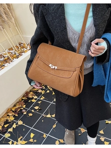 Detail view of the caramel leather texture and gold-tone metal twist lock on the bag