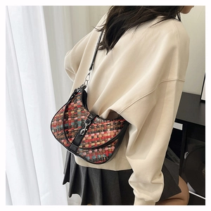 Detailed view of the multi-color woven patterns and leather strap on the half-moon bag