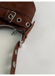 Detail of brown suede baguette bag featuring adjustable shoulder strap and silver hardware