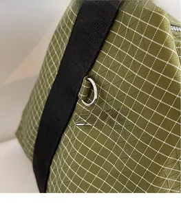Close-up of green checkered tote bag showing ripstop nylon fabric and silver D-ring