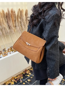 Detail of vintage caramel leather briefcase featuring a metal clasp and single handle