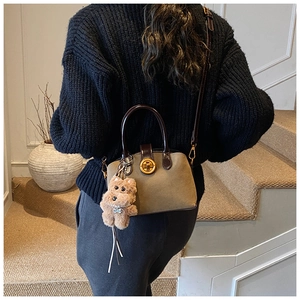 Retro suede shell bag in khaki with brown leather handle and puppy charm on model