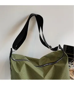 Detail of green checkered tote bag with adjustable black shoulder strap and zipper