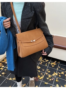 Brown vintage faux leather crossbody bag with gold twist lock shown in autumn street setting