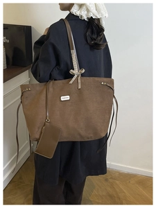 Detail of dark brown suede tote bag featuring fashion label and detachable pouch