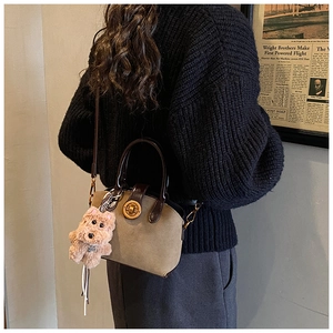 Detail of vintage suede shell bag featuring khaki contrast leather and golden metal clasp