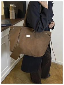 Braune Wildleder-Einkaufstasche mit Fashion-Label und kleinem Anhänger am Modell getragen