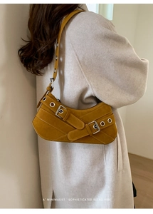 Detail of mustard yellow suede baguette bag with metal eyelets and crossover belts