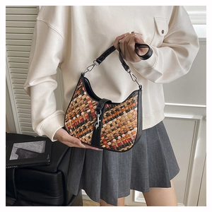 Macro shot of bohemian woven hobo bag with colorful patterns and black leather strap details