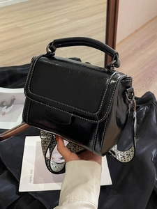 Chic black glossy leather crossbody bag with stylish black and white wave pattern wide strap