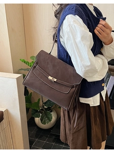 Close-up of a vintage dark brown shoulder bag featuring a gold twist-lock and matte leather
