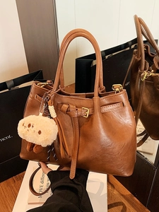 Brown leather tote handbag with white plush sheep charm and adjustable shoulder strap