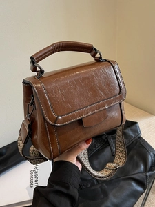 Retro brown oiled leather shoulder bag with white stitching and patterned wide strap