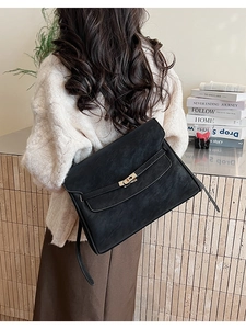 Detail of a large black vintage briefcase with gold buckle and smooth suede texture