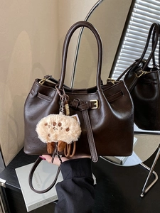 Fashionable dark brown leather bucket bag with gold buckle and plush charm for women