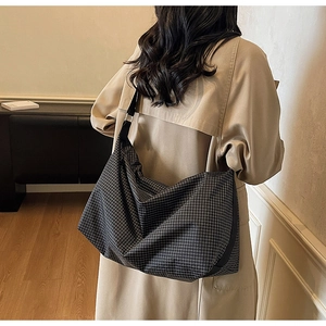 Detail view of large checkered tote bag with wide adjustable shoulder strap on model