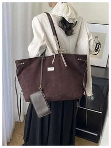 Detail of dark brown suede tote bag featuring a decorative brown checkered bow on strap