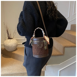 Detail of a brown vintage bucket bag with quilted stitching and a heart pattern scarf