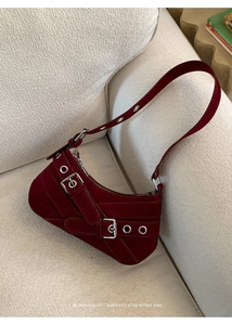 Détail d'un sac à bandoulière en daim bordeaux avec boucles rétro et œillets en argent