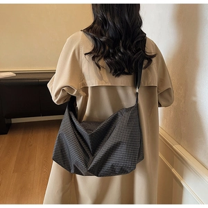 Detailed view of checkered hobo bag with adjustable wide shoulder strap and metal buckle