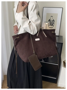 Detail of suede tote bag featuring a checkered bow ribbon and fashion label tag