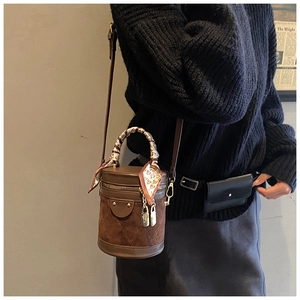 Detail of a brown patchwork bucket bag with quilted texture and silk scarf handle