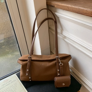 Detail view of a vintage brown crossbody bag with metal buckles and mini coin purse charm