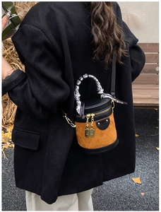 Detail of quilted brown suede bucket bag with black leather trim and silk scarf handle