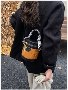 Outdoor shot of a brown bucket bag with scarf-wrapped handle on a wool coat