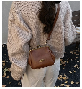 Vue extérieure d'un sac en cuir marron avec plaque en métal et bandoulière réglable