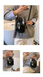 Detail of black cylindrical bucket bag with decorative heart scarf and gold hardware
