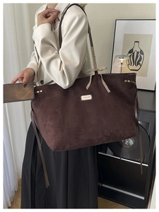 Deep brown suede tote bag with fashion tag and checkered bow shown in a chic room