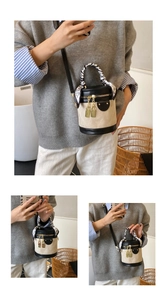 Detail of a khaki bucket bag with black leather trim, gold locks, and heart scarf handle
