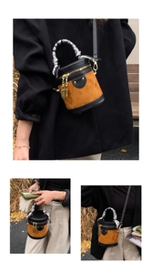 Close-up of brown suede bucket bag featuring black trim and silk scarf wrapped handle