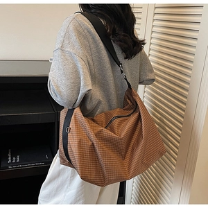 Macro view of brown plaid tote bag texture with durable fabric and sturdy black strap