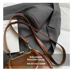 Gros plan du sac bandoulière vintage marron avec fermoir métal et bandoulière réglable