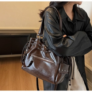 Détail d'un sac cabas en cuir marron brillant avec clous argentés et cordon de serrage